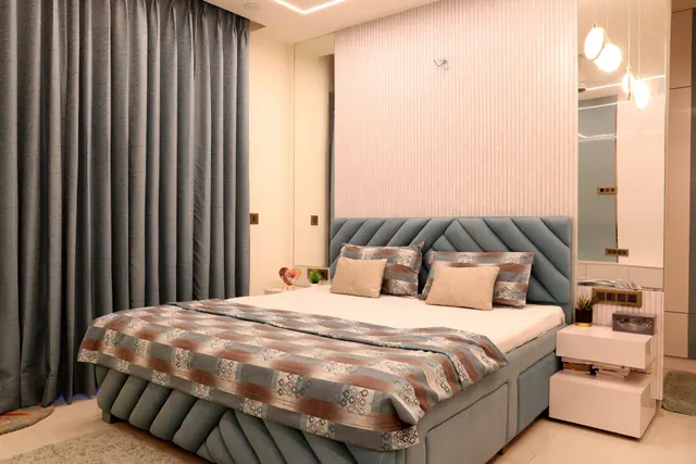 Warm-toned bedroom with upholstered headboard, study corner, and geometric LED accent wall