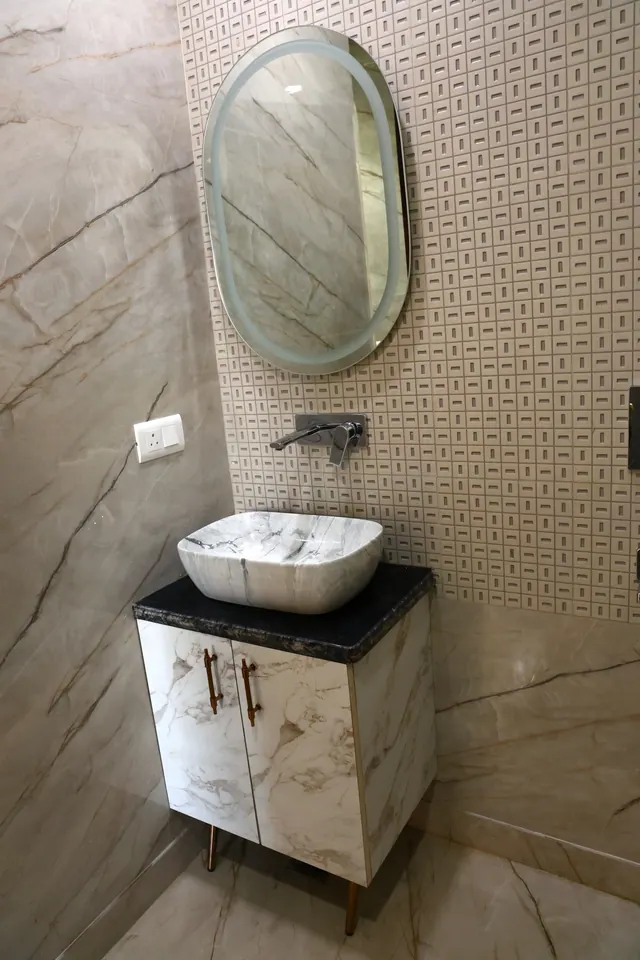 Floating vanity with dark stone finish, brass accents, and a white countertop basin